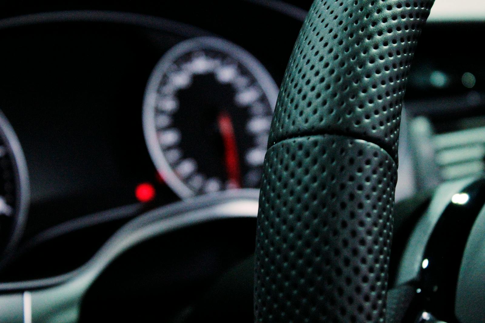 Close-up view of a car's modern steering wheel and dashboard with focus on design and technology.